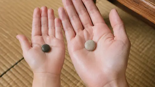 大人と子どもの手のひらに、小石がひとつずつ乗っている写真。